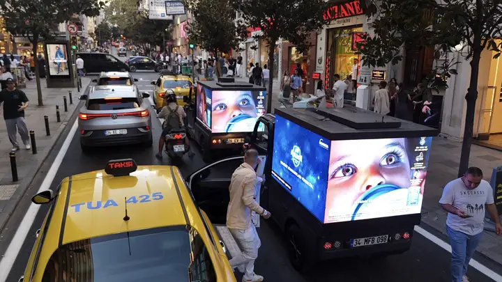 Taksinin yanında çocuk yüzlü kampanya yayınlayan mini LED araç