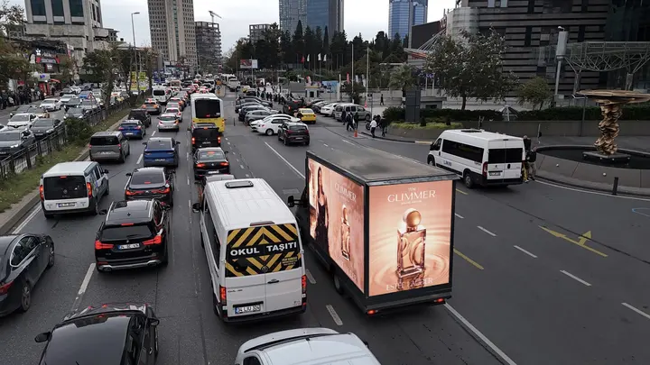 Gökdelenler arasındaki trafikte parfüm reklamlı LED araç
