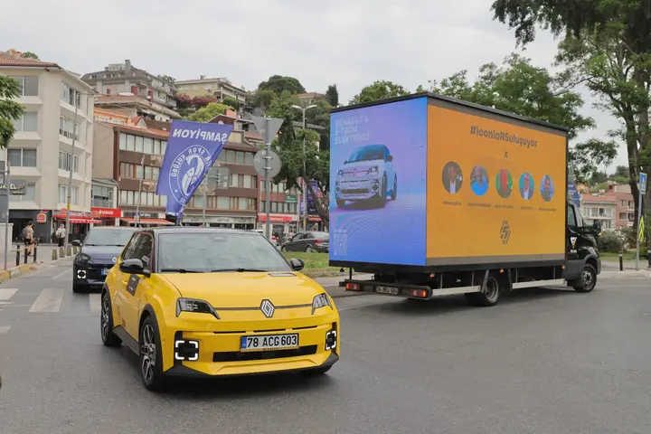 Sarı bir otomobille yan yana ilerleyen LED reklam aracı