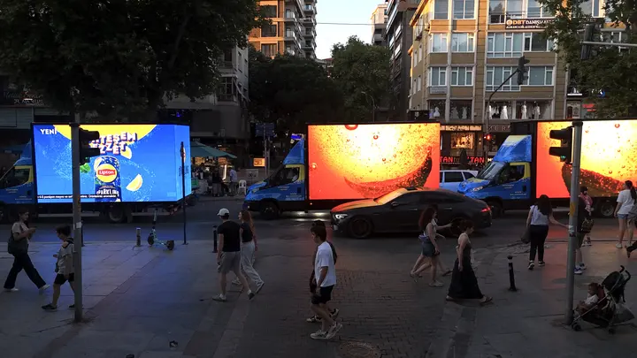 Yayaların arasında yan yana yayın yapan LED araçlar